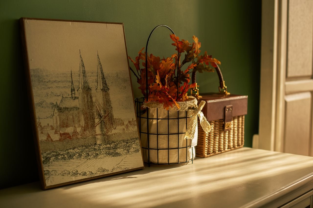 Vintage art and autumn decor on a warm-lit shelf, evoking a cozy atmosphere.